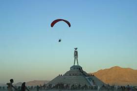 Paraglider sails around the Man at sunset
