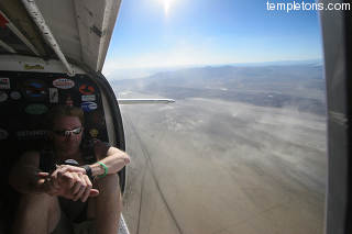Skydiving plane flies with Black Rock City and the playa in the background, jumper ready to leap out soon.