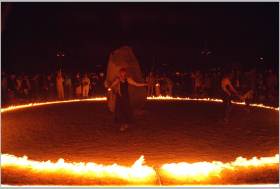 Woman lights a ring of fire for dance ceremony after the burn.
