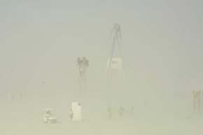 Always dust storms.  The man would vanish, then reappear as he is doing here.  Crew are adjusting him for the burn, while a documentary crew tests out their crane platform for shooting the burn.