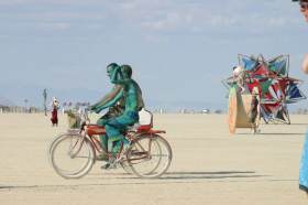 Green body-painters ride by my camp