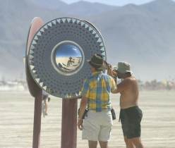 Man photographs self in spherical mirror inside art piece