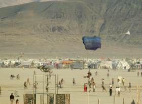 Tandem skydiver takes woman in for landing on Playa as onlookers are surprised