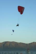 Two paragliders sail together over sunset in Black Rock City