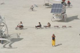 Chain of wagons rides by solar car and mastodon