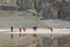 The tourists walk out from the Badwater visitor station to wade in the lake.