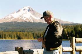 An old fisherman ties his hook at the dock at Trillium Lake, Mt. Hood in the background.